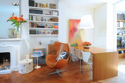 Living contemporáneo con sillón naranja, estantería blanca y piso de madera — proyecto Santa Fe, por Estudio Diez Muzzio, en CABA