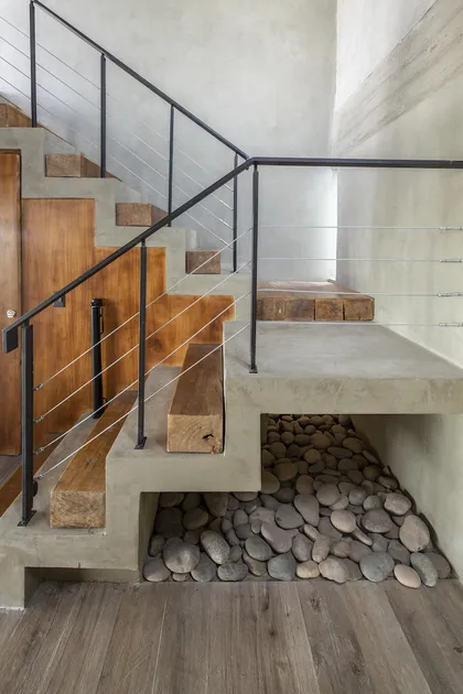 Escalera de madera con barandal hierro y detalle piedra debajo — proyecto Casa ES, por Facundo Arana Arquitecto