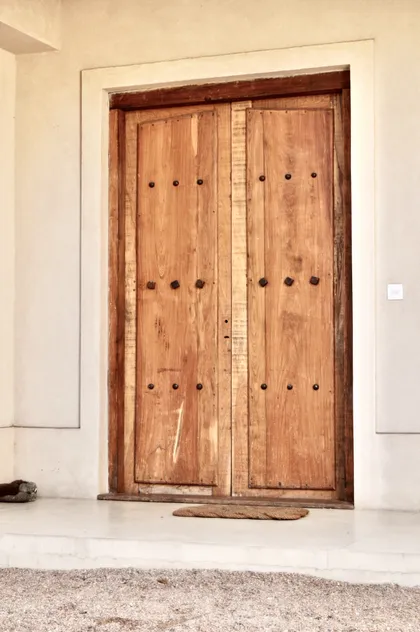 Detalle de puerta doble de madera rústica con remaches — proyecto Newman Benavidez, por Marconi Silva Arquitectos, en Benavidez
