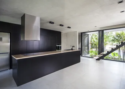 Cocina moderna abierta con isla negra y vista al jardín — proyecto Black House, por V2 Arquitectos, en City Bell