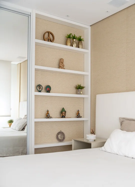 Dormitorio minimalista con estanterías blancas en pared beige y espejo — proyecto APARTAMENTO AV, por Marcia Debski Interiores