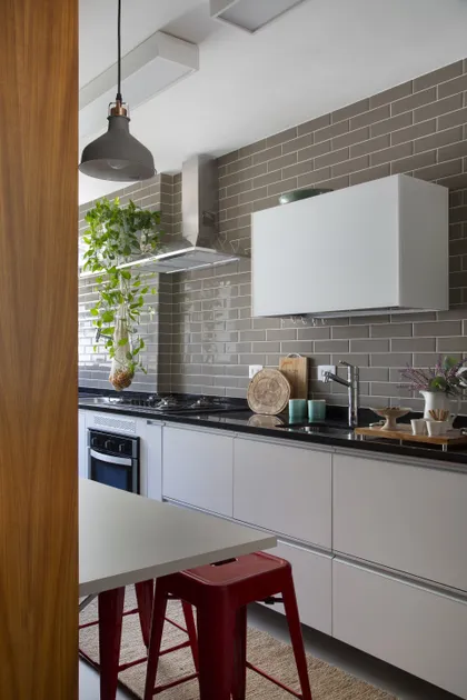 Cocina moderna blanca con ladrillo visto y banquetas bordo — proyecto Projeto Barão da Torre, por Kelly Figueiredo Arquitetura