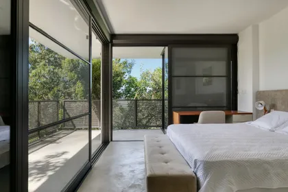 Dormitorio moderno con cama blanca y terraza con vista al jardín — proyecto Casa das Pedras, por Tetro Arquitetura