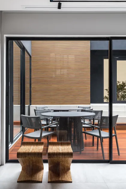 Terraza moderna con pared de listones de madera, mesas redondas y sillas grises — proyecto Bidese Recepcao, por Boscardin Corsi Arquitetura
