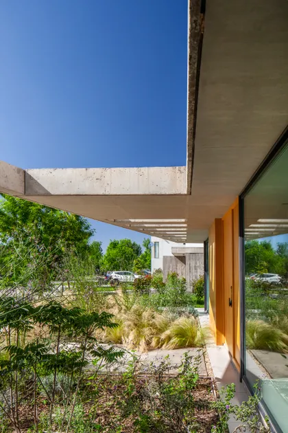 Fachada moderna con concreto expuesto y vegetación exuberante — proyecto Casa ALVA, por V2 Arquitectos, en City Bell