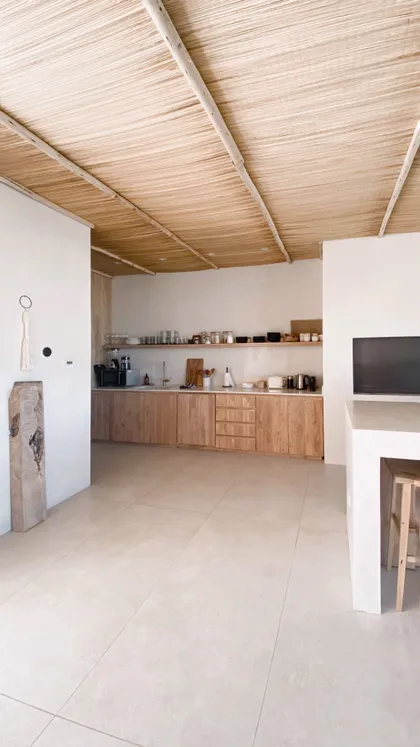 Cocina minimalista con techo de paja y muebles de madera natural — proyecto El Refugio, por Grupo Pauta Arquitectura, en Pinamar