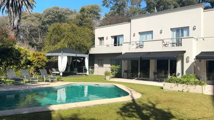 Amplio jardín con piscina moderna y fachada blanca — proyecto Villa Isidro Hotel Boutique & Spa, por Hermann Arquitectos, en San Isidro