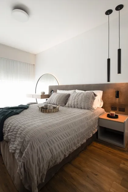 Dormitorio moderno con cama grande, luces colgantes cilíndricas y suelo de madera oscura — proyecto Artilleros Plaza, por C - ESTUDIO, en Buenos Aires