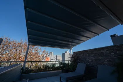 Terraza de balcón moderno con toldo retráctil y vista urbana — proyecto TOLDER - PERGOLAS, por Argentina en Obra 2024, en Rincón de Milberg