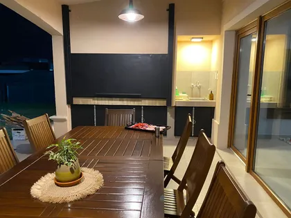 Comedor exterior de madera bajo pérgola con plantas — proyecto Casa El Rebenque, por Arq. Leonardo  De Lorenzi , en Canning