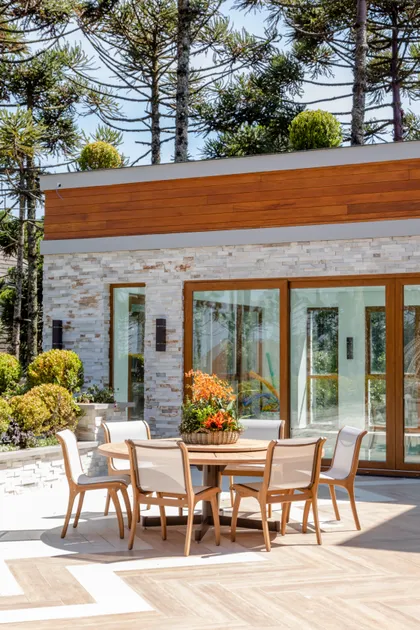 Terraza moderna con pisos de madera y muros de piedra y grandes ventanales — proyecto Projeto Destaque Club&Casa, por OKA ARQUITETURA