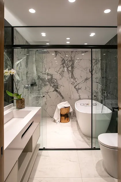 Baño moderno con mármol, banera blanca y ducha con cristal negro — proyecto Casa Oroño, por Estudio Plats, en Buenos Aires