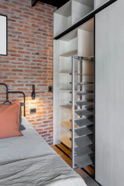 Dormitorio industrial con pared de ladrillo expuesto y ropero minimalista — proyecto JURAMENTO, por Nima Estudio, en Buenos Aires