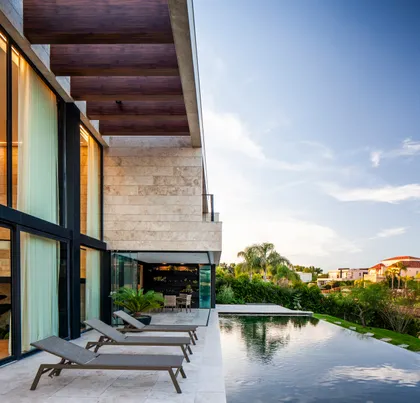 Piscina infinita moderna con deck de madera y vista al mar — proyecto Casa Porsche, por Remy Arquitectos, en Buenos Aires
