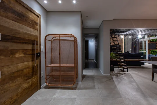 Pasillo moderno con escalera de madera y ventanal doble altura — proyecto Duo Morumbi, por Pricila Dalzochio