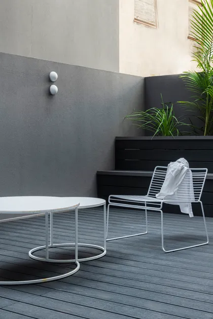 Patio moderno con silla y mesa de metal blanco, muro gris y plantas — proyecto Proyecto Junin, por Alejandra Nusenovich, en Buenos Aires