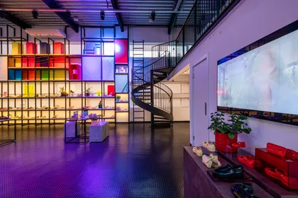 Espacioso pasillo con escalera helicoidal, muebles modulares iluminados y pantalla — proyecto Showroom Melissa, por Pricila Dalzochio