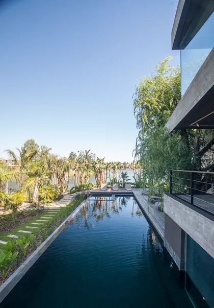 Piscina infinita moderna con vegetación tropical y arquitectura de concreto — proyecto Casa Nomade, por Remy Arquitectos, en B1648 Tigre