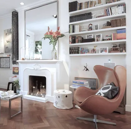 Living moderno con chimenea blanca, sillón de cuero y biblioteca empotrada — proyecto Santa Fe, por Estudio Diez Muzzio, en CABA