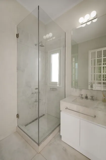 Baño moderno con ducha de esquina en vidrio y revestimientos de mármol — proyecto Dpto AY, por Estudio Dado, en Recoleta
