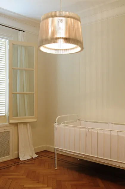 Cuna blanca en dormitorio con lámpara tejida y cortinas — proyecto Dpto LH, por Estudio Dado, en Recoleta