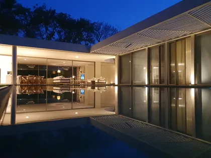 Residencia moderna de noche con piscina reflectante y luces cálidas — proyecto CASA DEL ARBOL, por Estudio Xime Fontan Balestra, en Tortuguitas