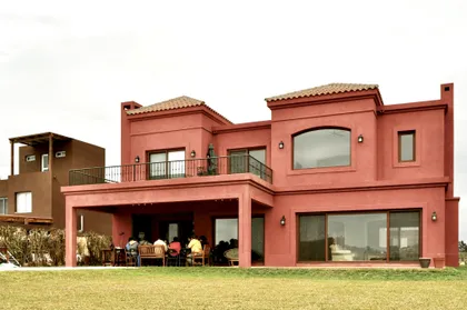 Casa moderna terracota con galería y amplios ventanales en el exterior — proyecto San Marcos 2, por Marconi Silva Arquitectos, en Benavidez