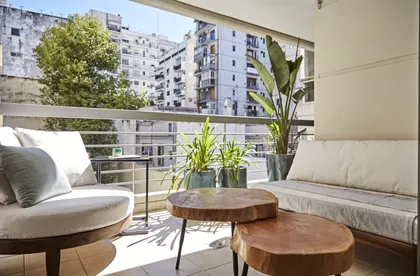 Balcón moderno con muebles de tela beige y mesas de madera apiladas — proyecto Proyecto Scalabrini Ortiz, por URBANO estudio, en Palermo