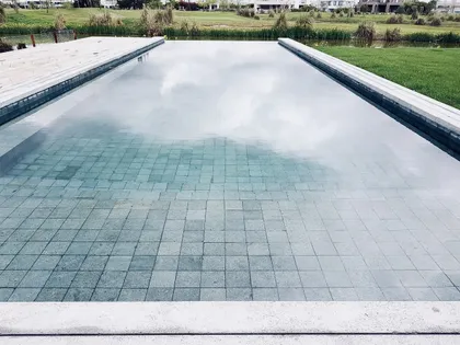 Piscina moderna de baldosas grises con reflejos de cielo — proyecto EL GOLF, NORDELTA , por Greschek Obras , en Nordelta