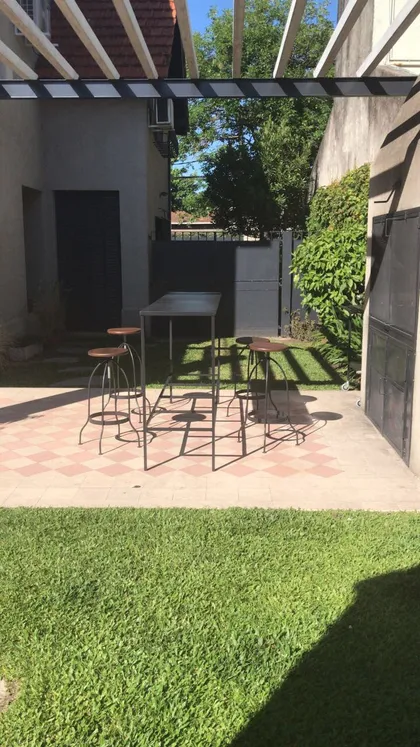 Patio exterior con mesa y banquetas de bar, estilo moderno industrial — proyecto Casa en Martinez, por Rioja Arquitectura, en Martínez