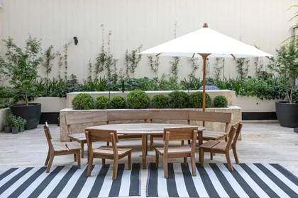 Comedor exterior con sombrilla, mesa de madera y jardín vertical — proyecto ARQ. TOMAS MAGRANE, por uchimayfotos, en CABA