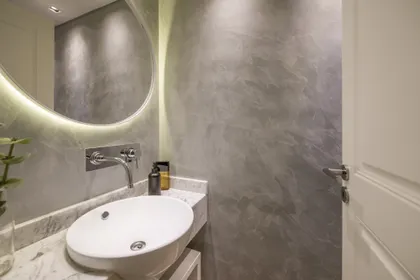 Baño moderno con lavabo ovalado blanco y espejo redondo retroiluminado — proyecto Segui, por Estudio Basa, en CABA