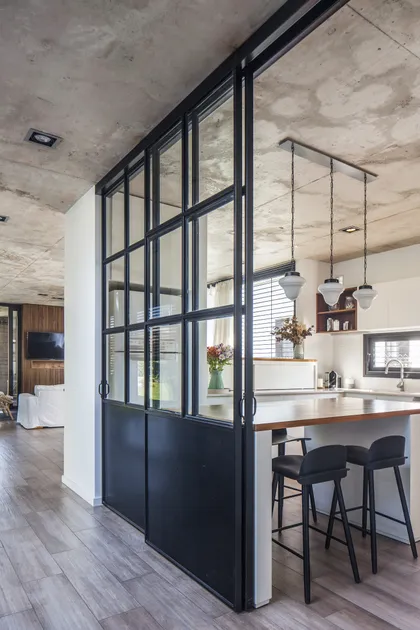 Cocina moderna con isla, partición de vidrio y concreto expuesto — proyecto Vivienda MI61, por Eg Arquitectura