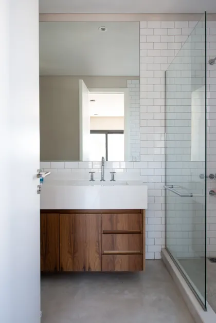 Baño moderno con mueble flotante de madera, azulejos blancos y ducha de cristal — proyecto EL ENCUENTRO , por Greschek Obras , en Benavidez