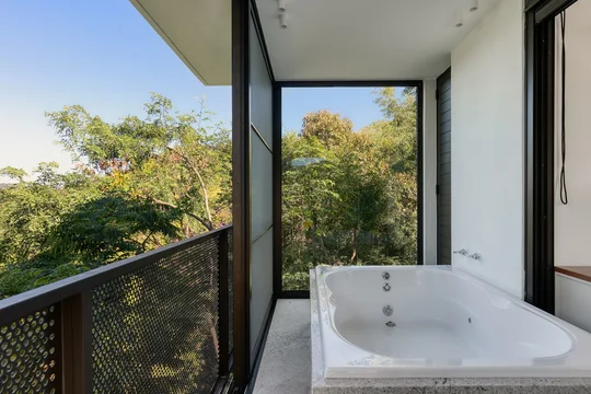 Bañera en terraza con vistas a bosque y ventanales modernos — proyecto Casa das Pedras, por Tetro Arquitetura