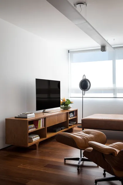Elegante living con muebles mid-century, madera oscura y ventanales amplios — proyecto Apartamento JB, por Boscardin Corsi Arquitetura
