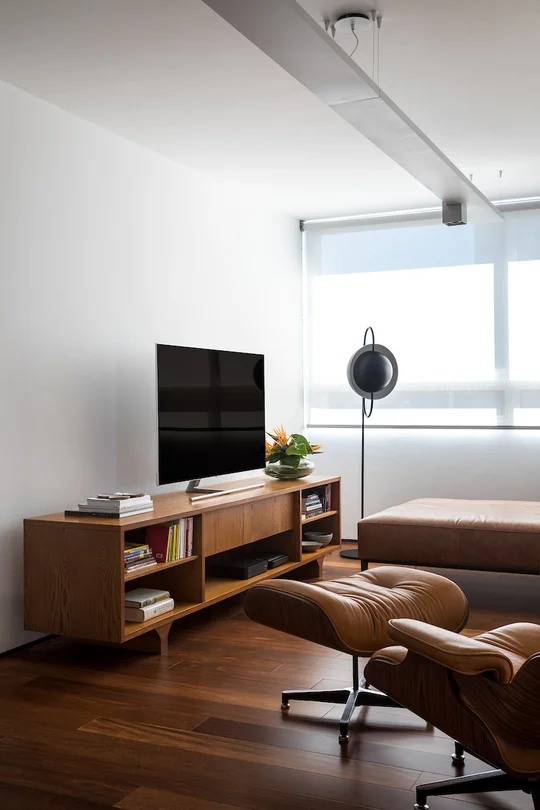 Elegante living con muebles mid-century, madera oscura y ventanales amplios — proyecto Apartamento JB, por Boscardin Corsi Arquitetura