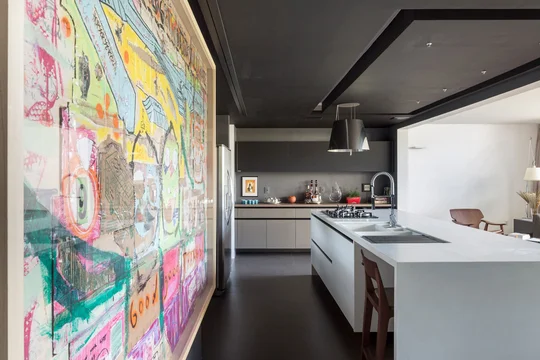 Cocina contemporánea con isla central blanca y pared de arte colorida — proyecto Apartamento 312S, por Coda Arquitetos