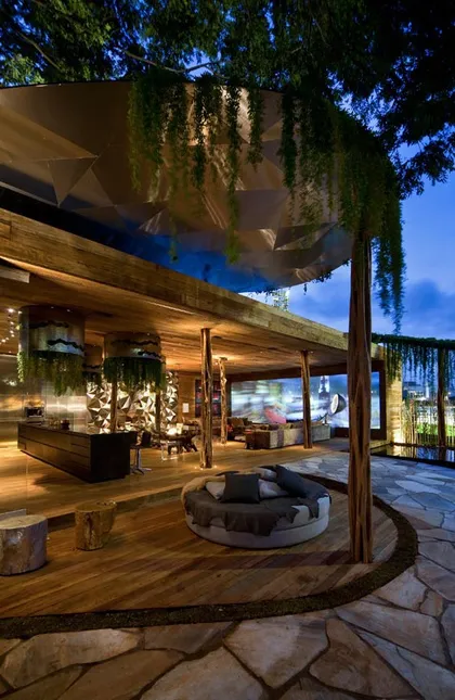 Quincho moderno con deck de madera, hogar circular y enramada iluminada — proyecto Arquitetura e Interiores II, por Demian Golovaty