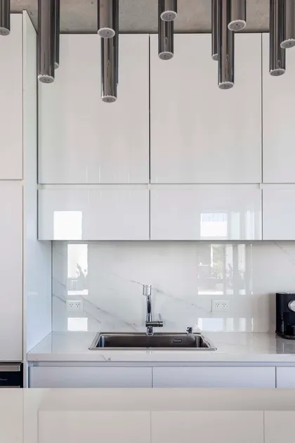 Cocina moderna con gabinetes blancos brillantes y encimeras de mármol — proyecto DISEÑO INTERIOR - CASA VISTAS, por FOCO_arquitectura&diseñointerior, en Belén de Escobar