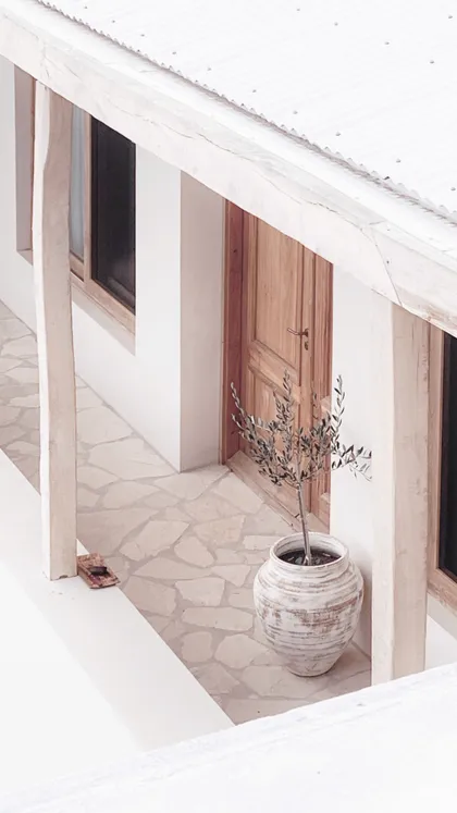 Fachada mediterránea con puerta rústica y macetero texturizado — proyecto El Refugio, por Grupo Pauta Arquitectura, en Pinamar