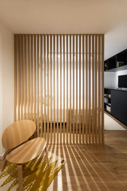 Dormitorio moderno con divisorio de madera y luz indirecta — proyecto REFORMA NE, por Rastro Estudio, en Palermo