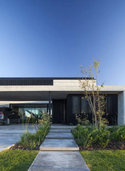 Fachada moderna con techo en voladizo y camino de hormigón — proyecto CASA FELIX, por GMARQ, en Pilar