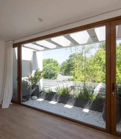 Terraza moderna con plantas y ventanales al jardín — proyecto CASA BaCa, por Alfredo Orfila arquitectura, en Benavidez