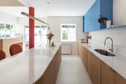 Cocina moderna con isla curva de cuarzo blanco y muebles azules — proyecto Grecia, por Bouré Studio, en Núñez