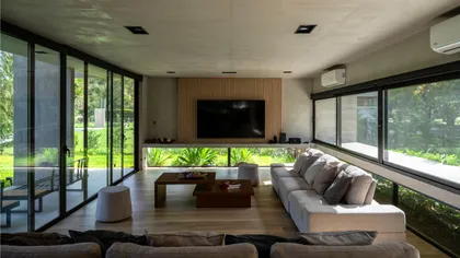 Living moderno con ventanales amplios y vista al bosque — proyecto Casa Miralagos II, por Besonías Almeida arquitectos, en La Plata