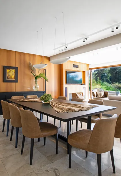 Comedor moderno con paredes de madera cálida y sillas tapizadas — proyecto Yatch, por Estudio Verde Concreto