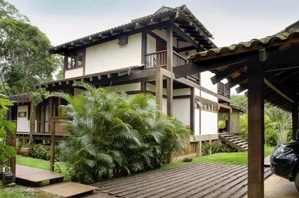 Casa colonial elevada con terraza de madera y vegetacion verde — proyecto Casa da Praia, por Celso Mellani