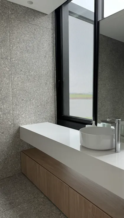 Baño moderno con ventana grande y vanitory de madera y piedra — proyecto Casa ENE, por Jorgelina Tortorici & asoc., en Nordelta