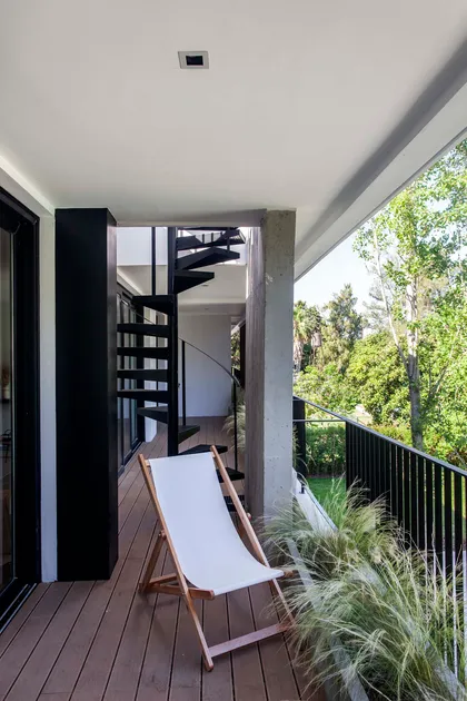 Terraza moderna con silla de lona, escalera caracol y vegetación — proyecto Alvear AV, por V2 Arquitectos, en City Bell